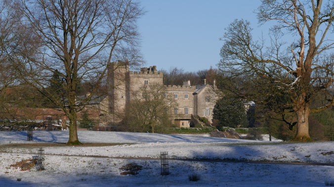 Sizergh Castle in the snow, viewed through the trees from the driveway